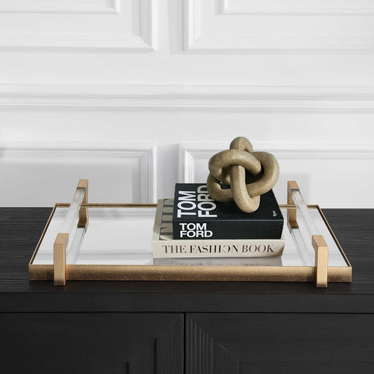 Mirrored gold tray with decorative coffee table books and knot sculpture.