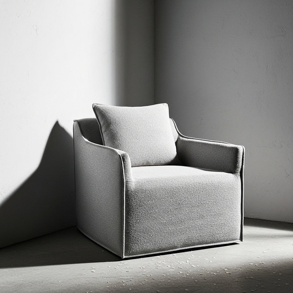 Gray armchair with a cushion against a plain wall