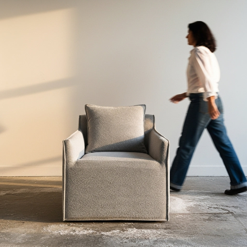 Gray armchair with a pillow in a room with a person walking by