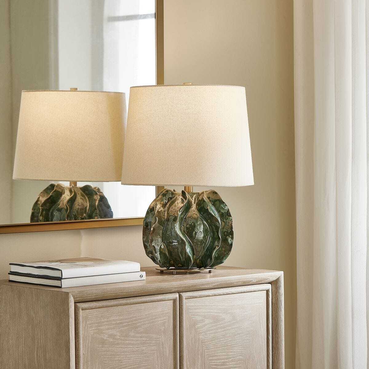 Two table lamps with marble bases on a wooden cabinet.
