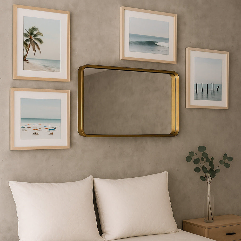 Bedroom with framed beach-themed artwork and a gold mirror on a beige wall.