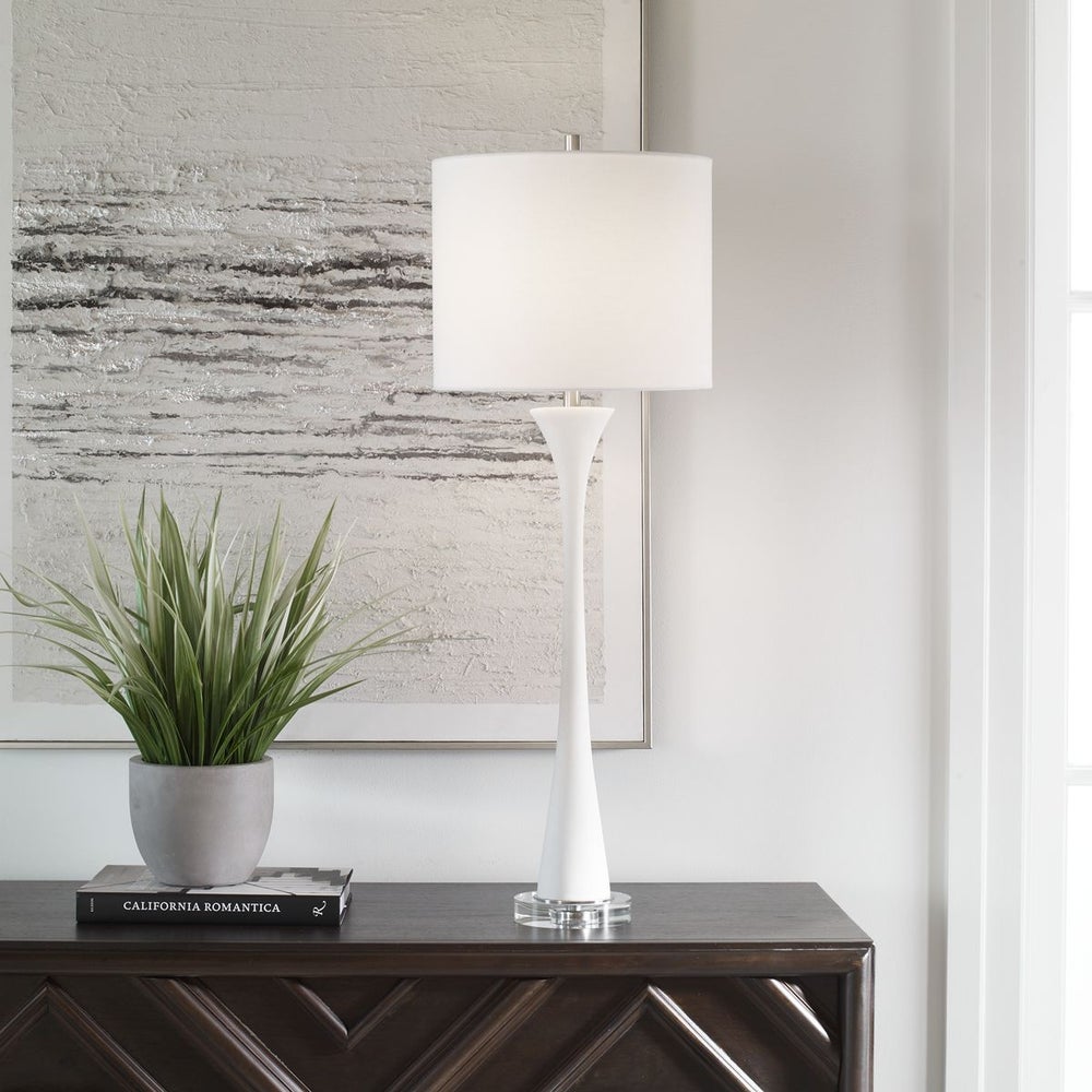 White buffet ivory table lamp on console with ocean art on wall showing behind it.