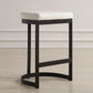 A Matte black iron framed counter stool with a white pebbled faux leather cushion.