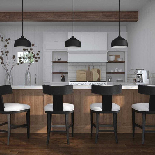 Klismos style counter stool featuring a curved charcoal black frame and a stone white cushion . Shows a grouping of stools seated along a long brown kitchen island.