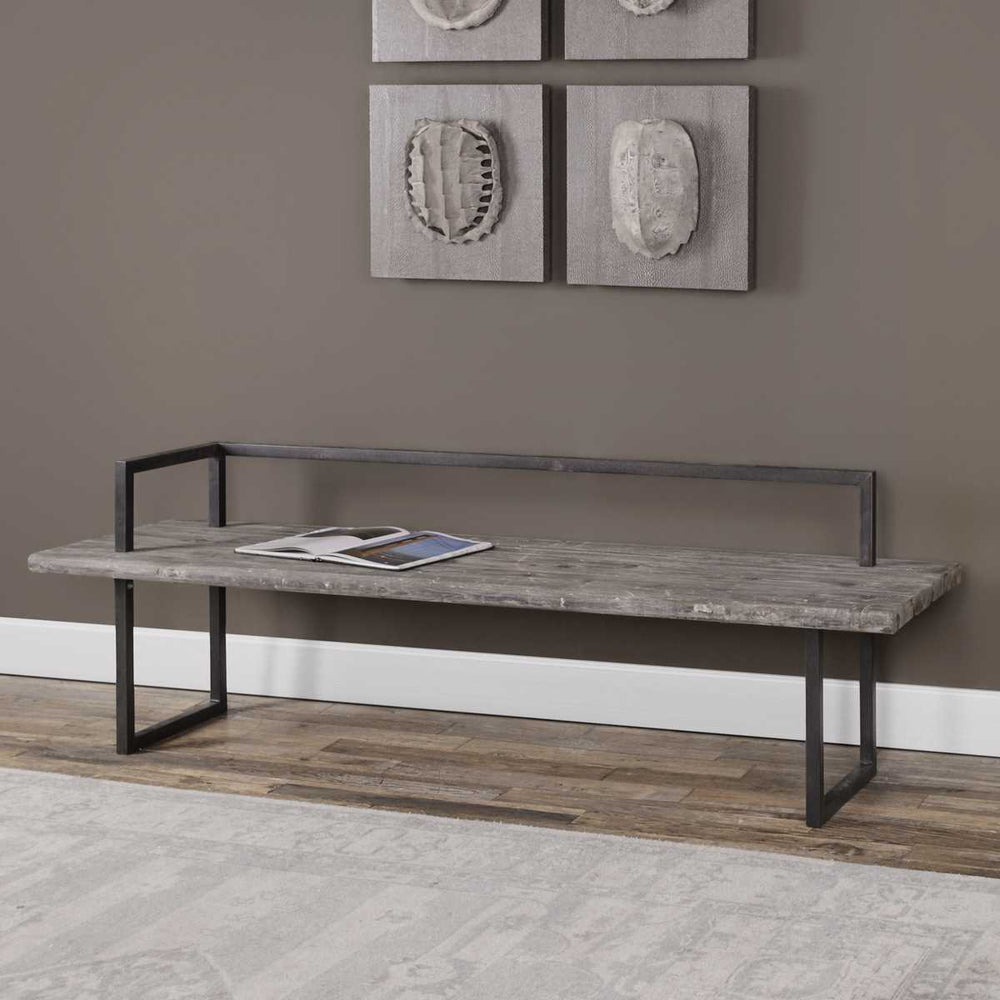 Gray bench with wooden surface and metal frame against a brown wall with decorative elements.