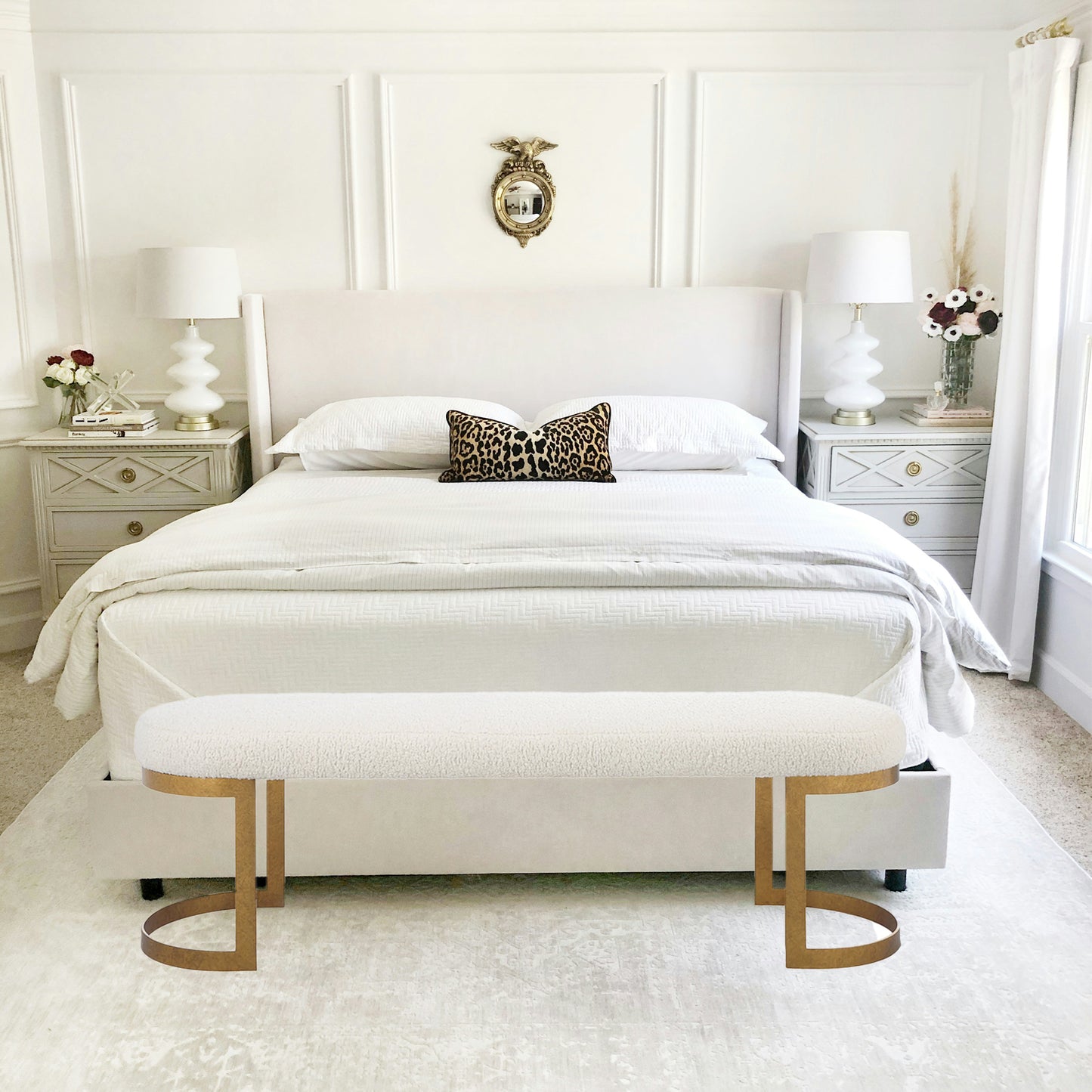 Gold Bench at the foot of a white bed in a bedroom.