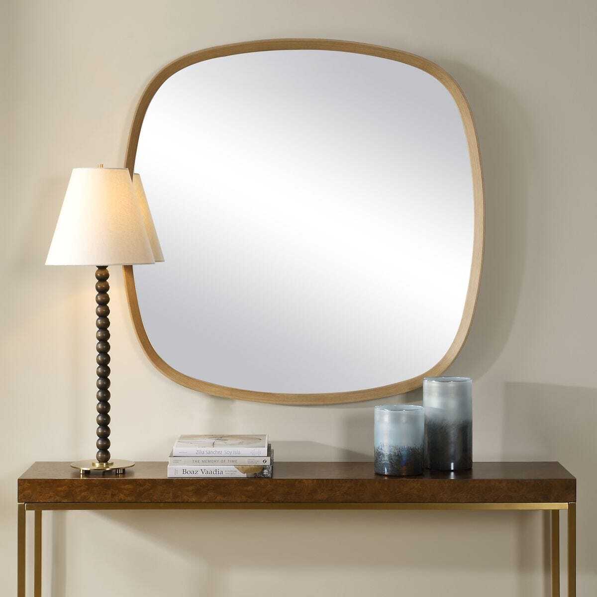 Wooden console table with mirror, lamp, and candles against a beige wall