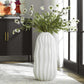 Large white decorative vase on the floor of a living room.