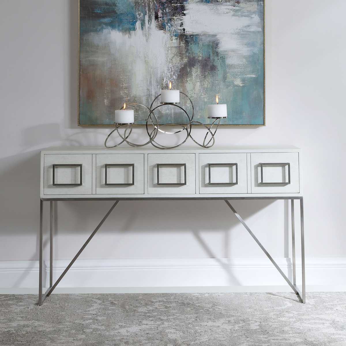 Console table with decorative candles and abstract painting in a room.
