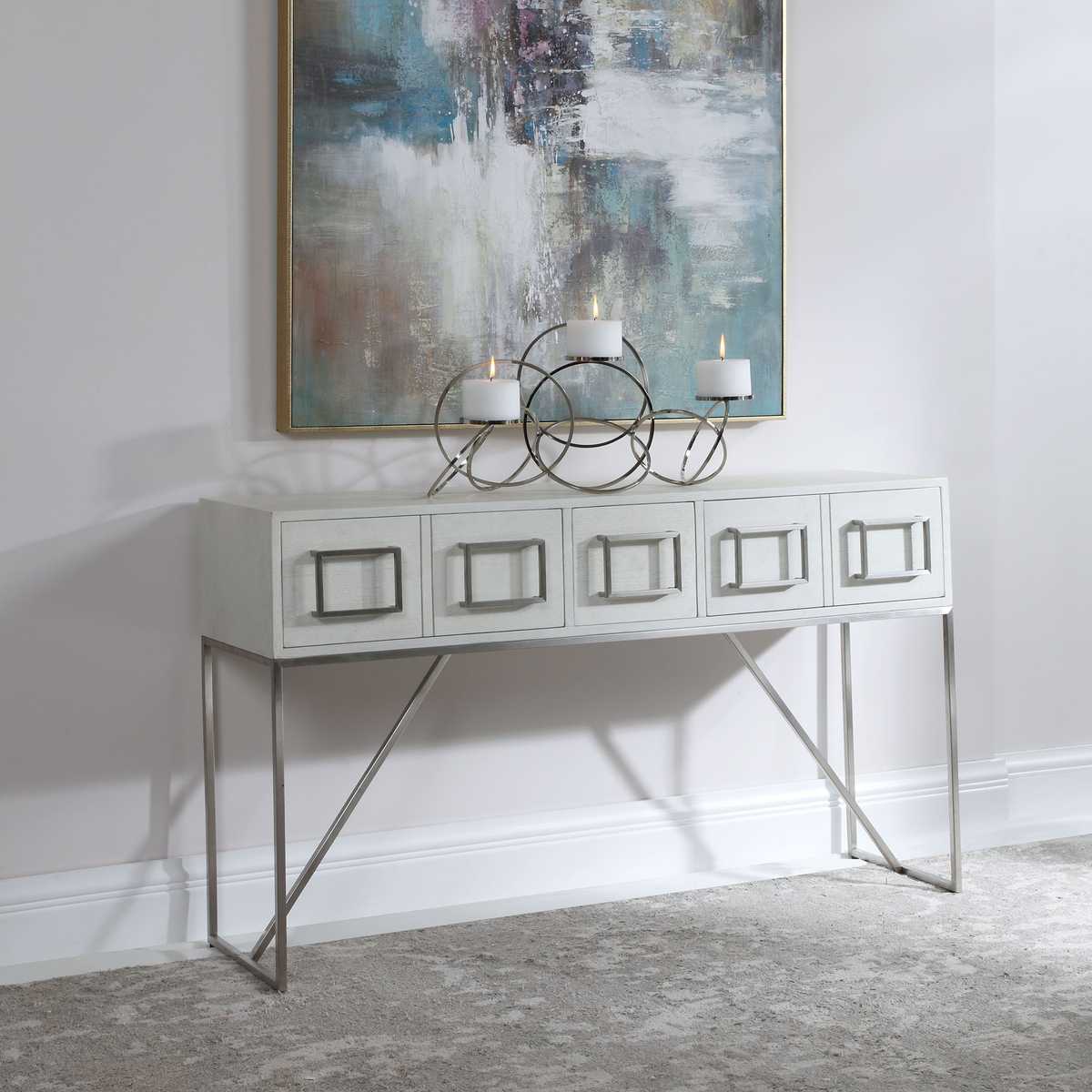 White console table with metal legs against a white wall with abstract art.