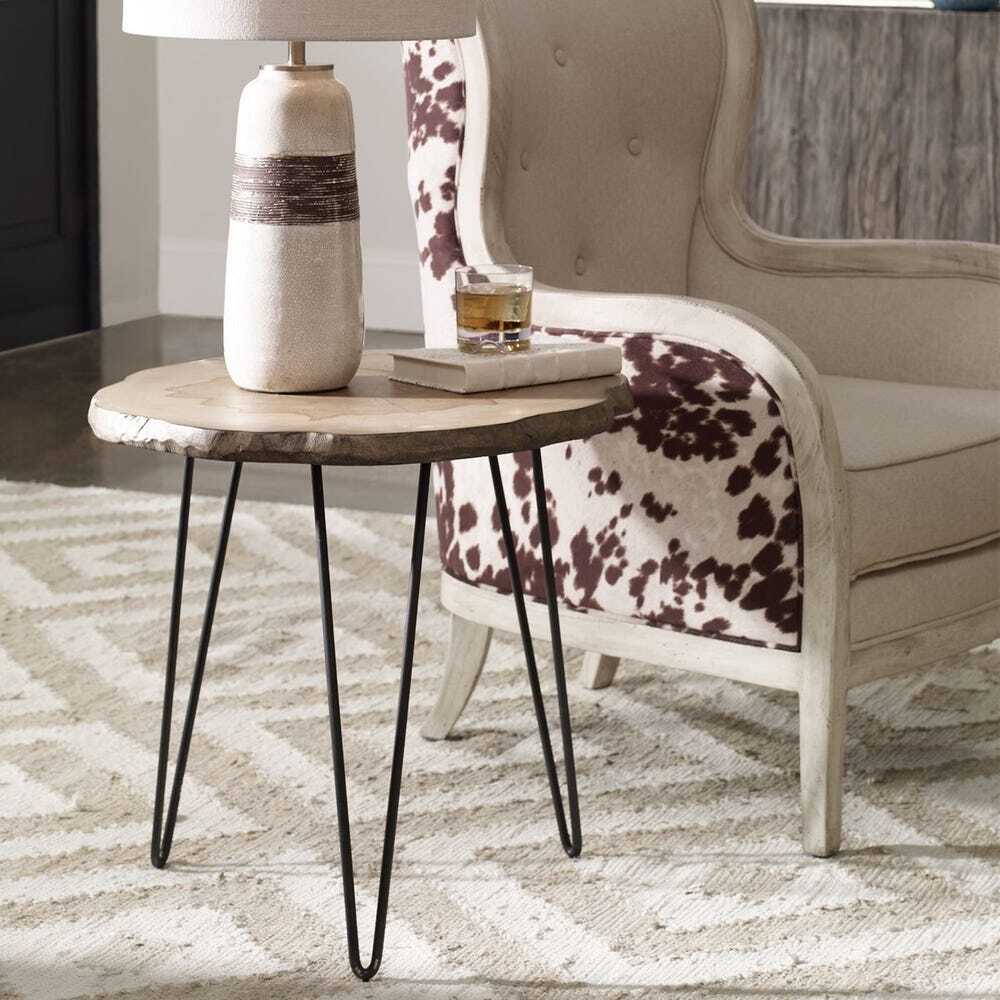 Small round table with black hairpin legs next to a chair with a cow print cushion.