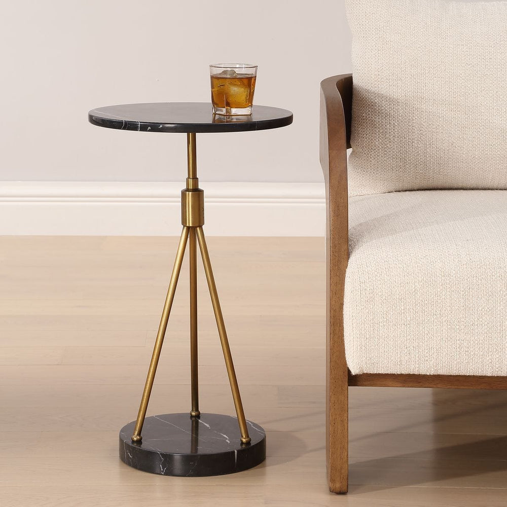 Small round side table with marble top and brass legs next to a beige sofa.