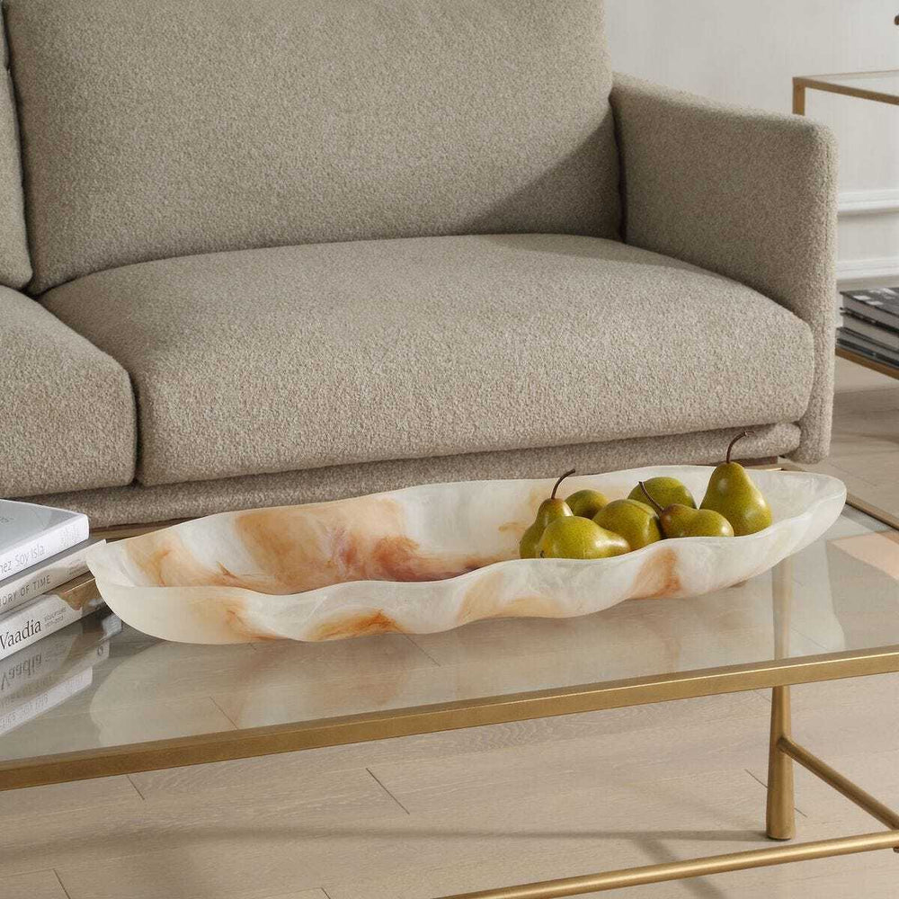Decorative tray with pears on a glass coffee table in a living room setting.