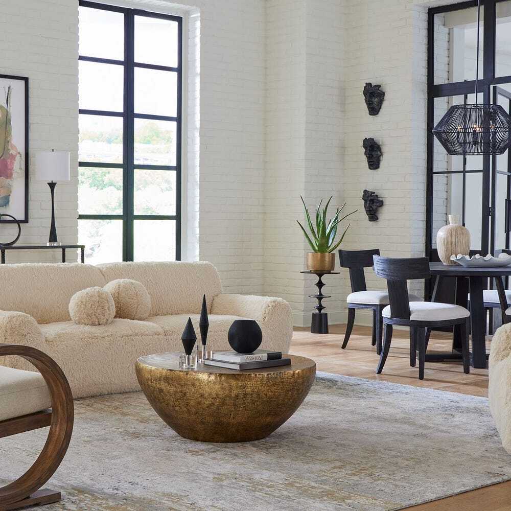 Modern living room with beige sofa, gold coffee table, and dining area.