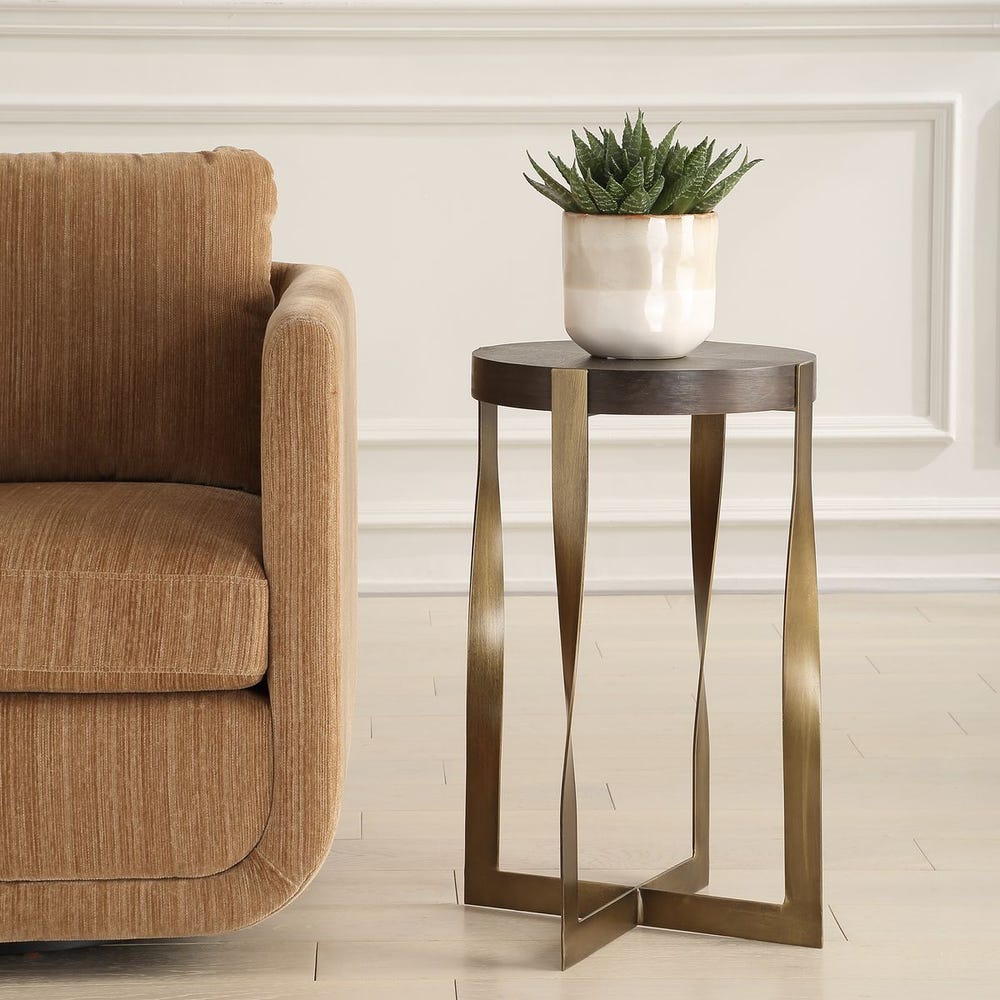 Bronze side table with a plant next to a brown armchair in a room.