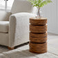 Wood accent table next to boucle armchair with plant on top.