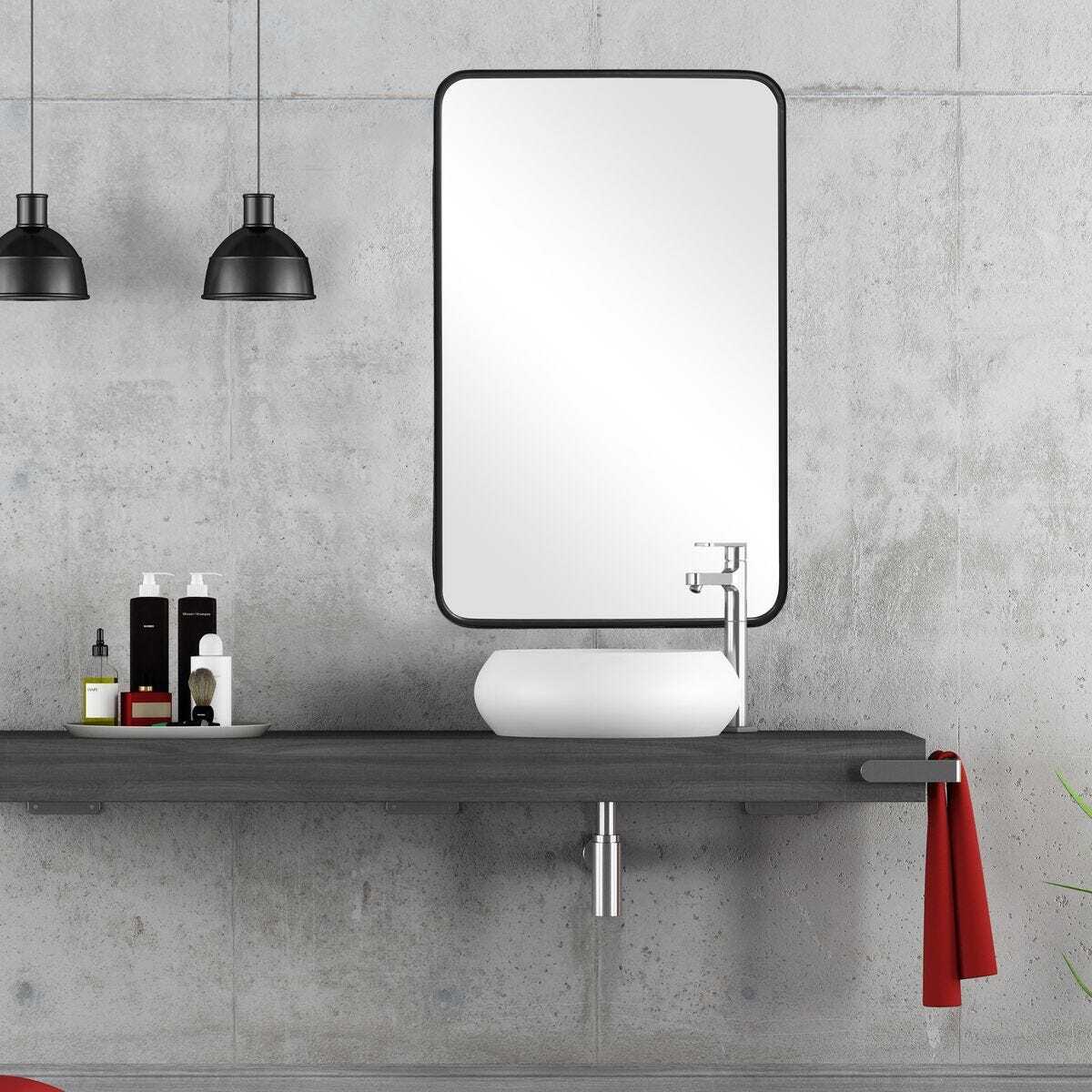 Bathroom setup with a mirror, sink, and shelf against a concrete wall.