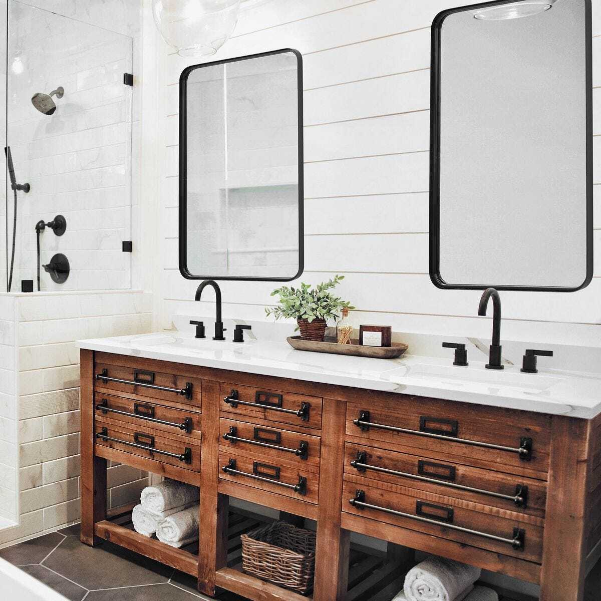 Bathroom with wooden vanity, white countertop, and two mirrors.
