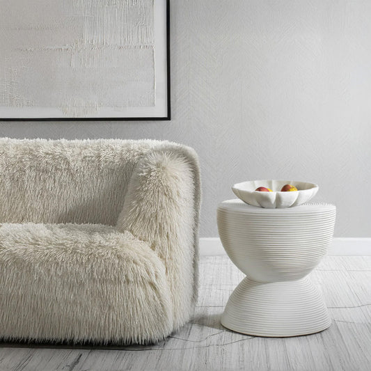 Modern white decorative bowl on white coastal end table with sofa in a coastal living room.