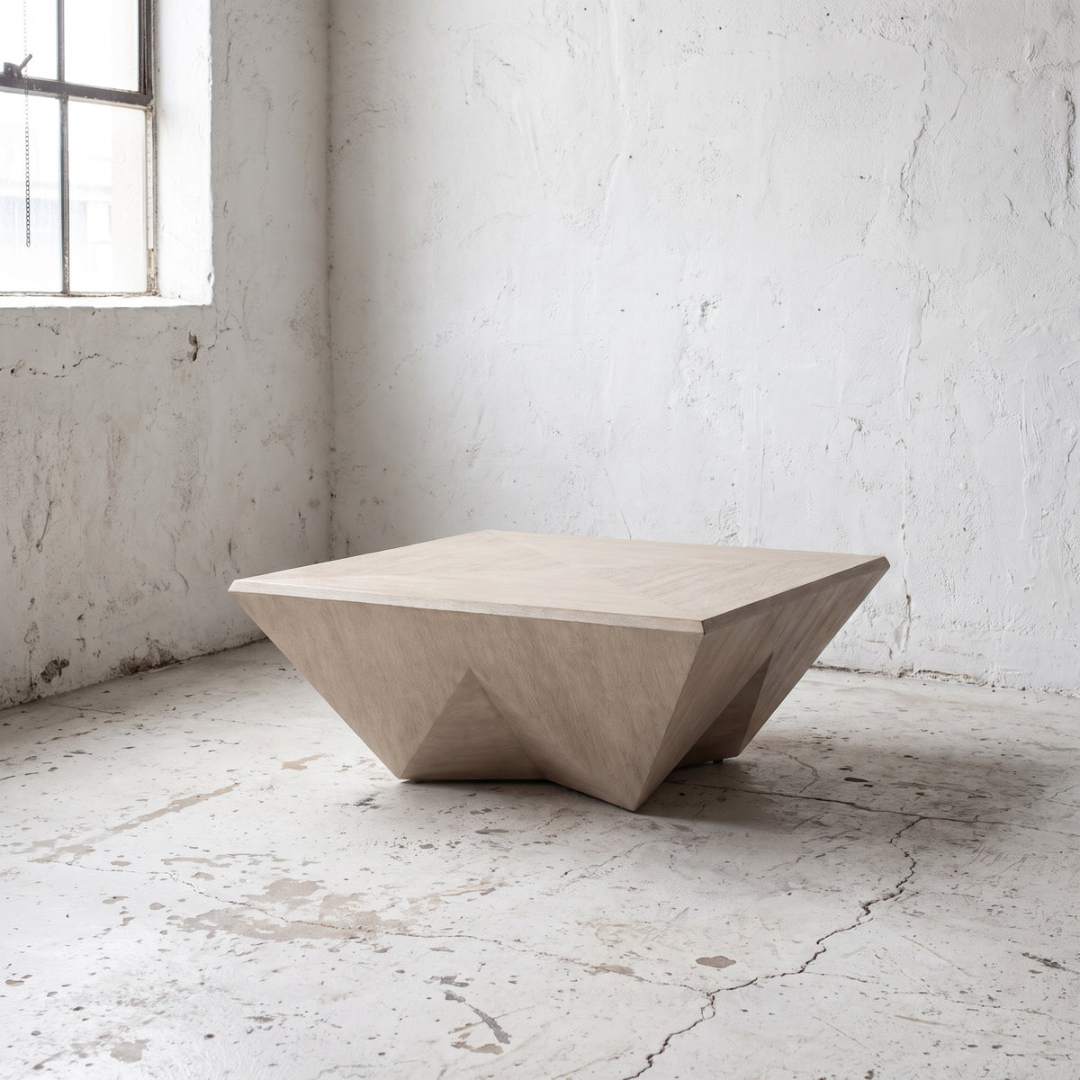 A modern geometric concrete coffee table in a light beige finish, set in a minimalist room with textured white walls and a concrete floor.