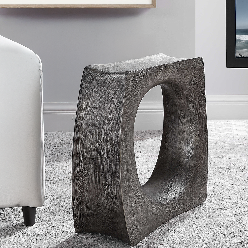 Modern grey accent able next to sofa on carpet with ocean view.
