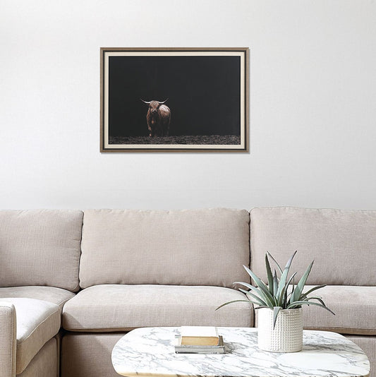 Image of modern highland cow art in rustic frame above tan sofa and white coffee table that is marble