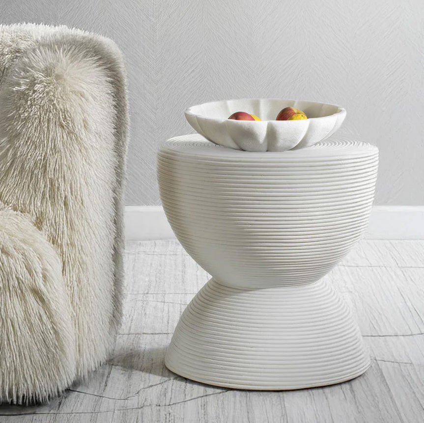 Close up of a white decorative end table with a white decorative bowl on top.