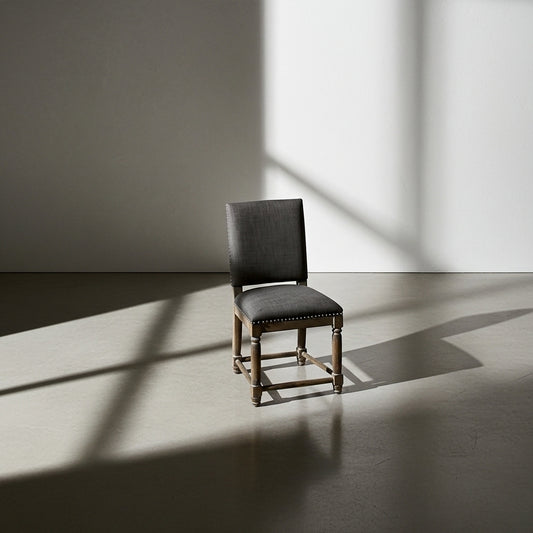 Gray upholstered chair with wooden frame on a white floor and wall