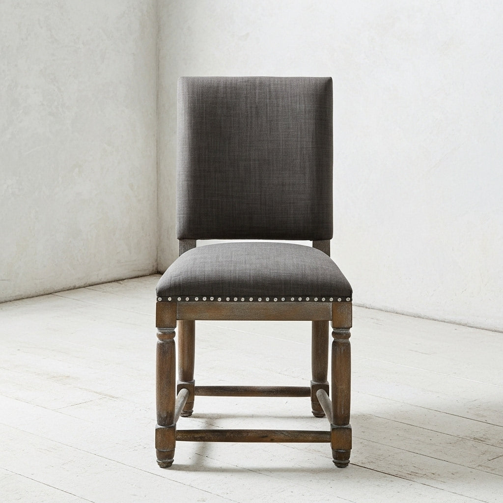 Gray upholstered chair with wooden frame on a white floor and wall