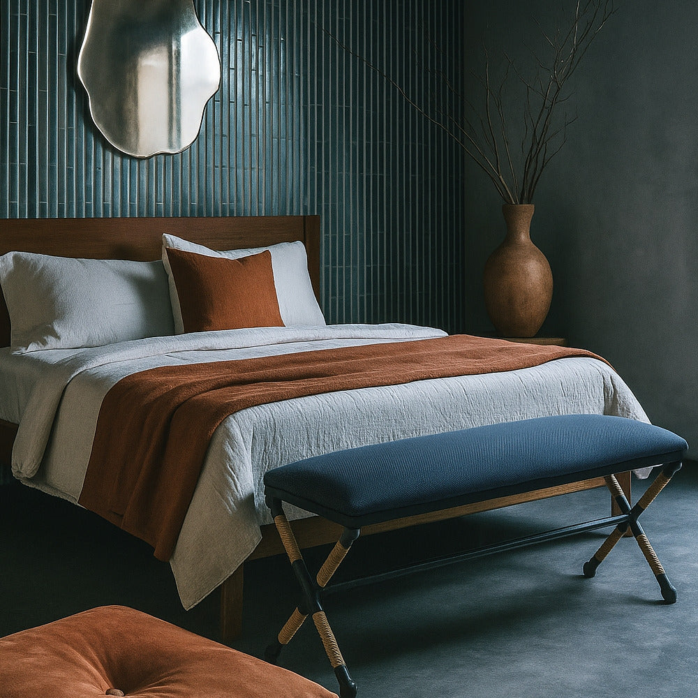 Bedroom with a bed, bench, and decorative items against a dark wall.