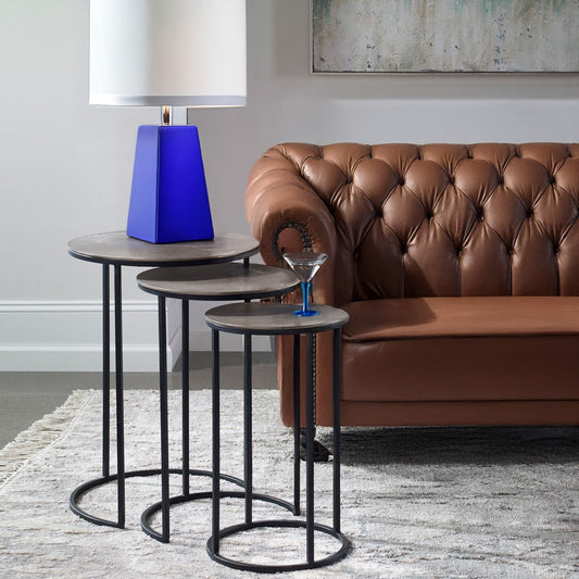 Nested side table with leather sofa and blue accent table lamp.