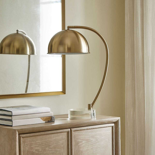 Gold table lamp with curved arm on a white background