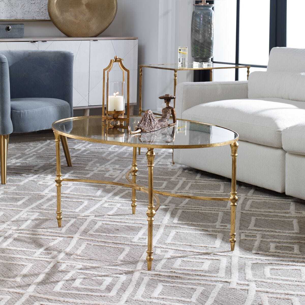 Gold coffee table in a living room with a white sofa and blue armchair.