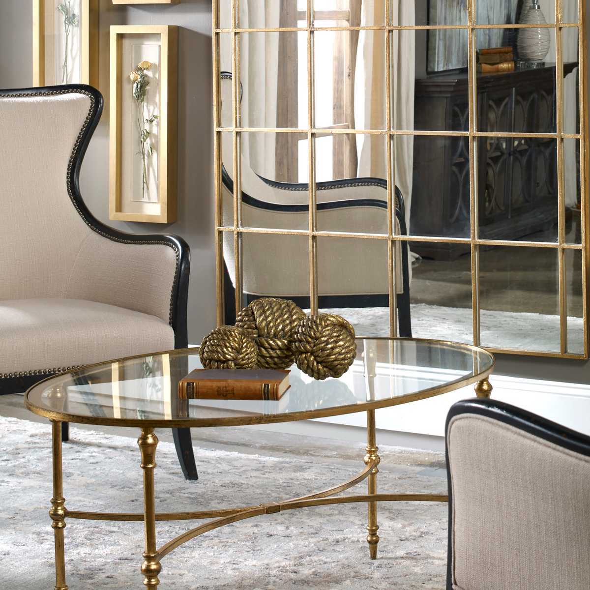 Decorative living room with a gold coffee table, chairs, and a large mirror.