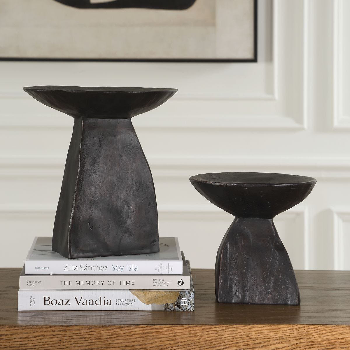 Two black pedestail bowls on a wooden surface with books underneath.