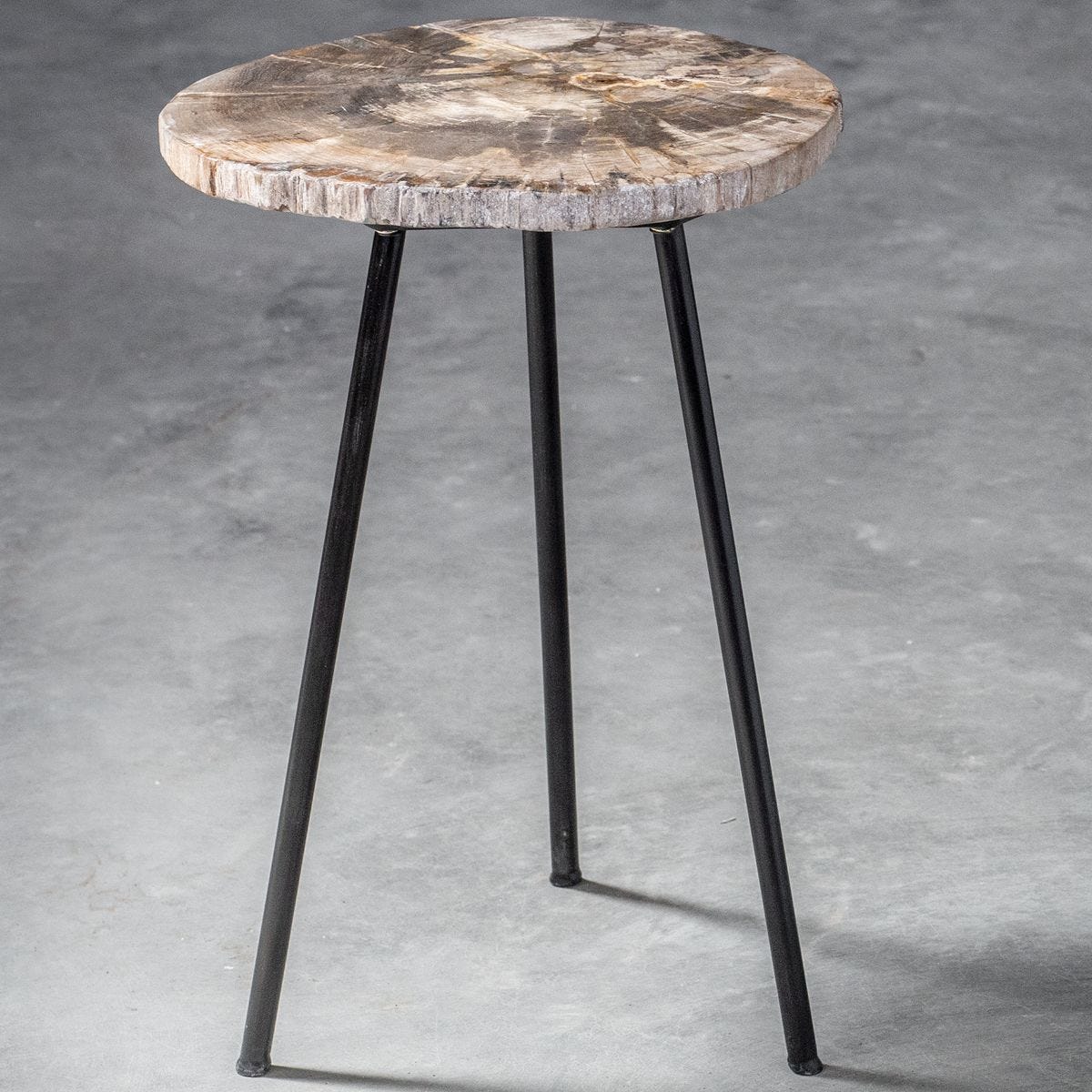 Small round table with wooden top and black metal legs on a gray concrete background