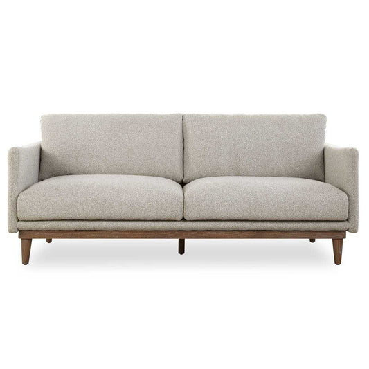 Living room with a beige sofa, glass coffee table, and wall art.