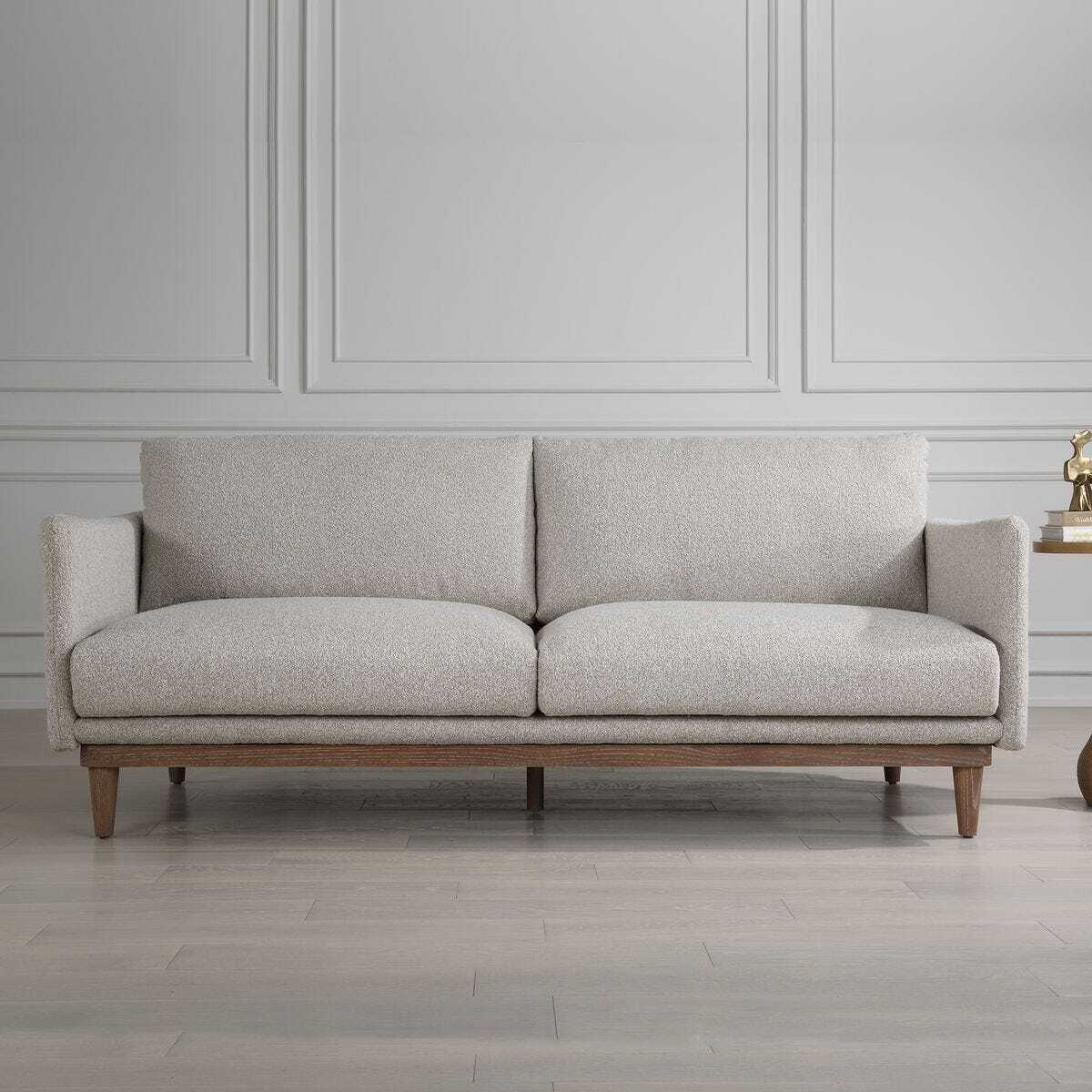 Gray sofa with wooden legs in a room with gray walls and wooden flooring