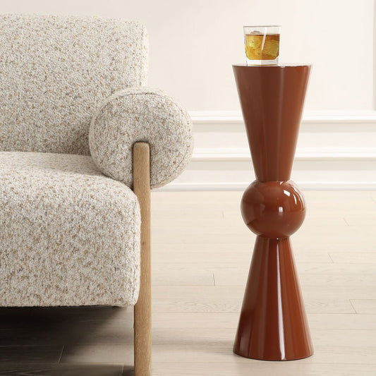 Modern pedestal side table in living room in Terra Cotta with a drink on top with a decorative arm chair.