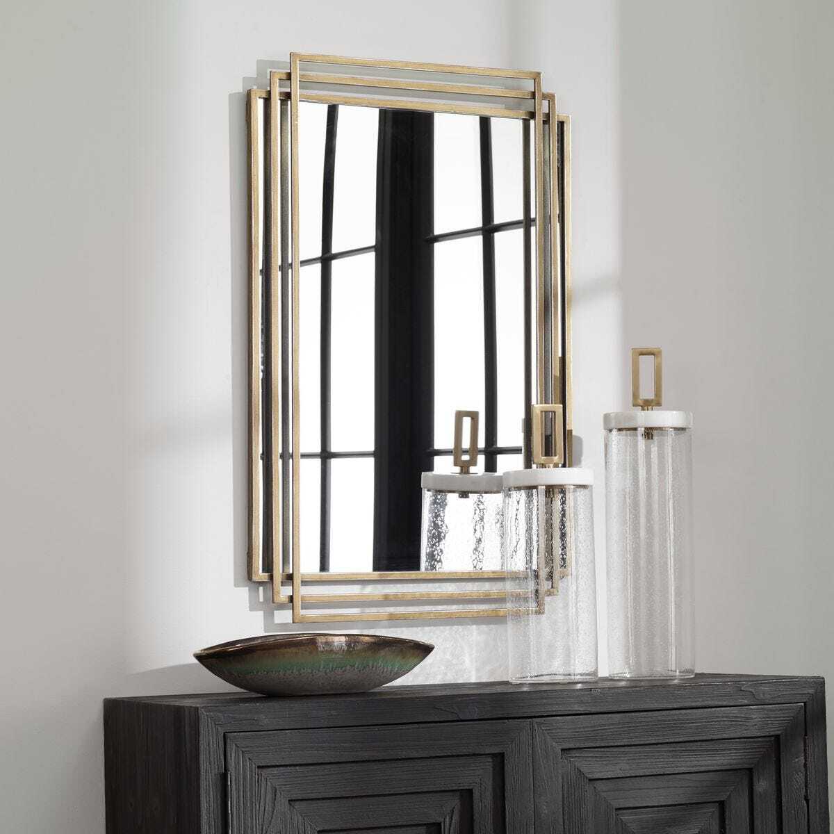 Decorative mirror with gold frame on a white wall above a dark wooden console table.