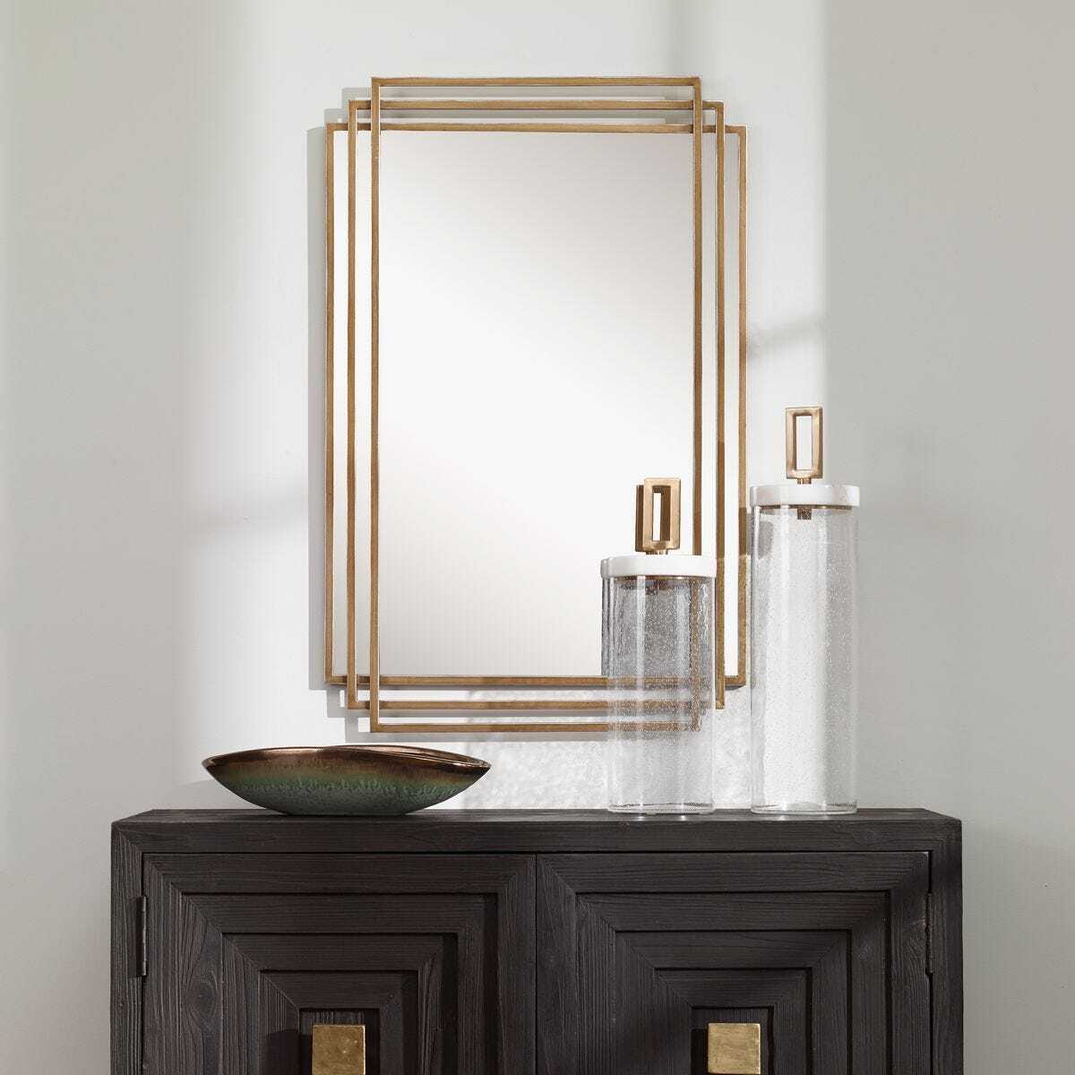 Decorative mirror with gold frame on a wall above a dark wooden console table.