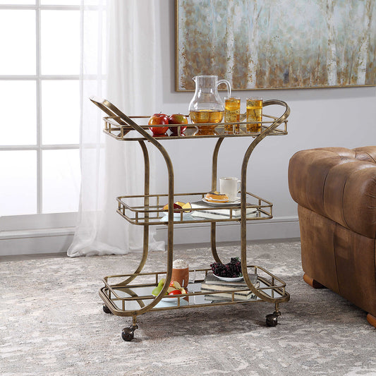 Antiqued gold bar cart on wheels in living room.