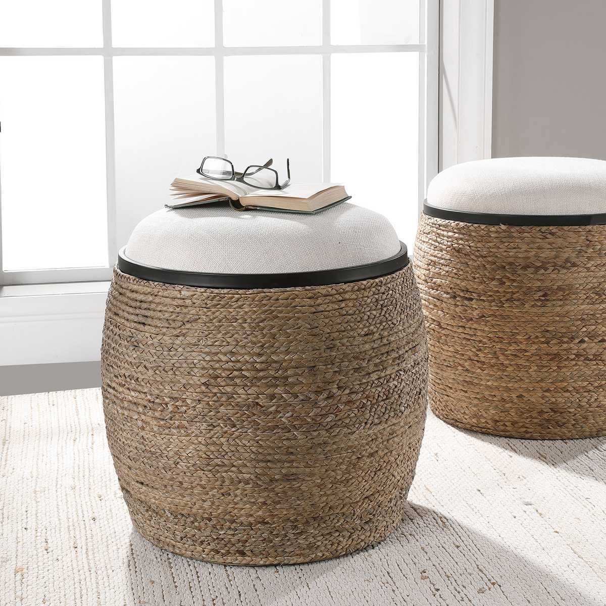 Two round woven stools with cushioned tops in a room with a window.
