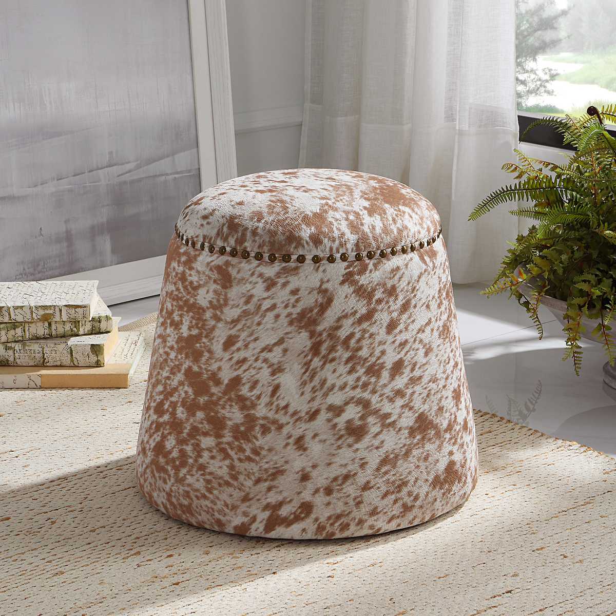 Round cowhide ottoman brow and white.