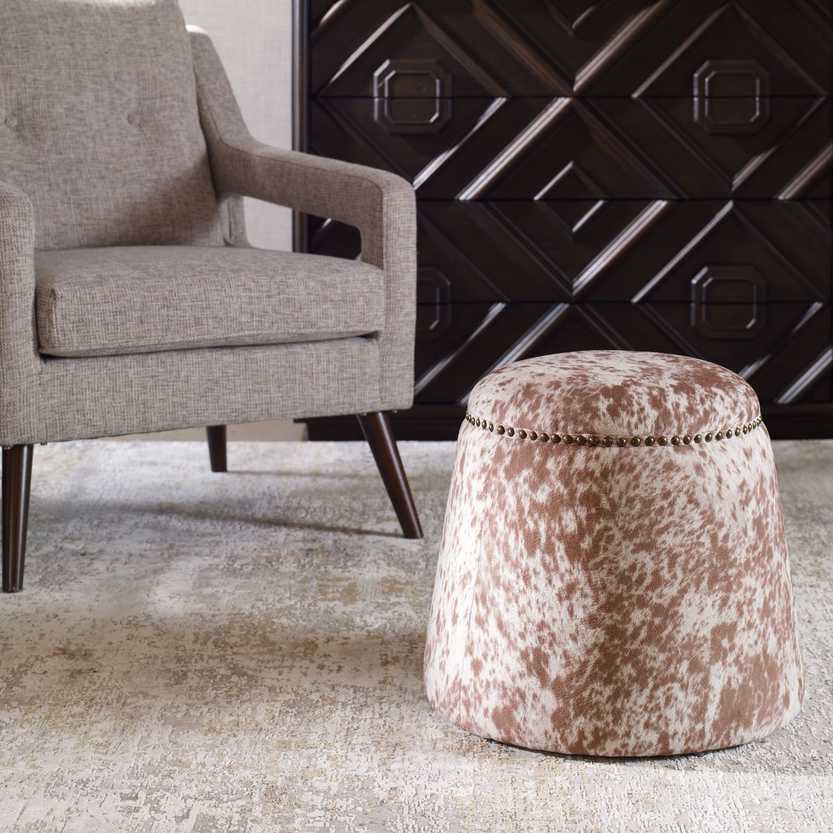 Round cowhide ottoman in living room in brown and white.