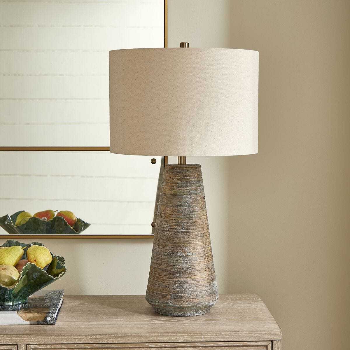 Table lamp with textured base on a wooden surface, with a neutral background