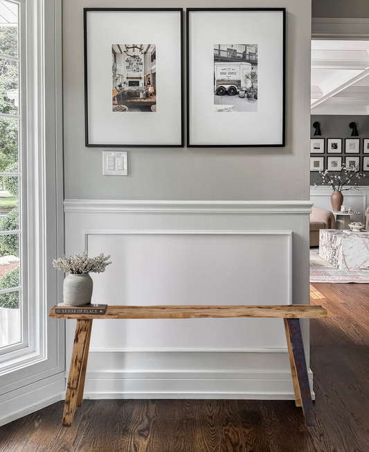 Entry bench made with distressed wood in a mudroom with pot and book. Two pieces of art hanging above.