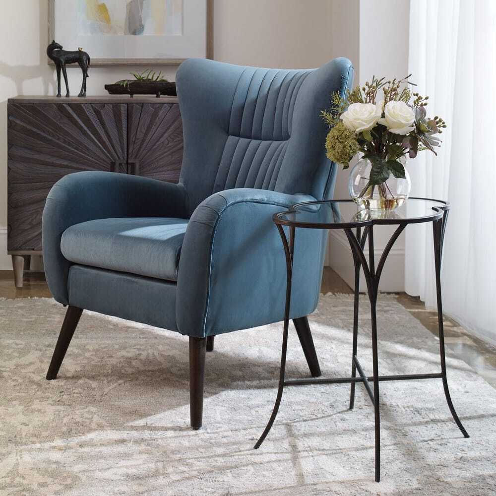 Blue armchair in a room with a small table and decorative items.