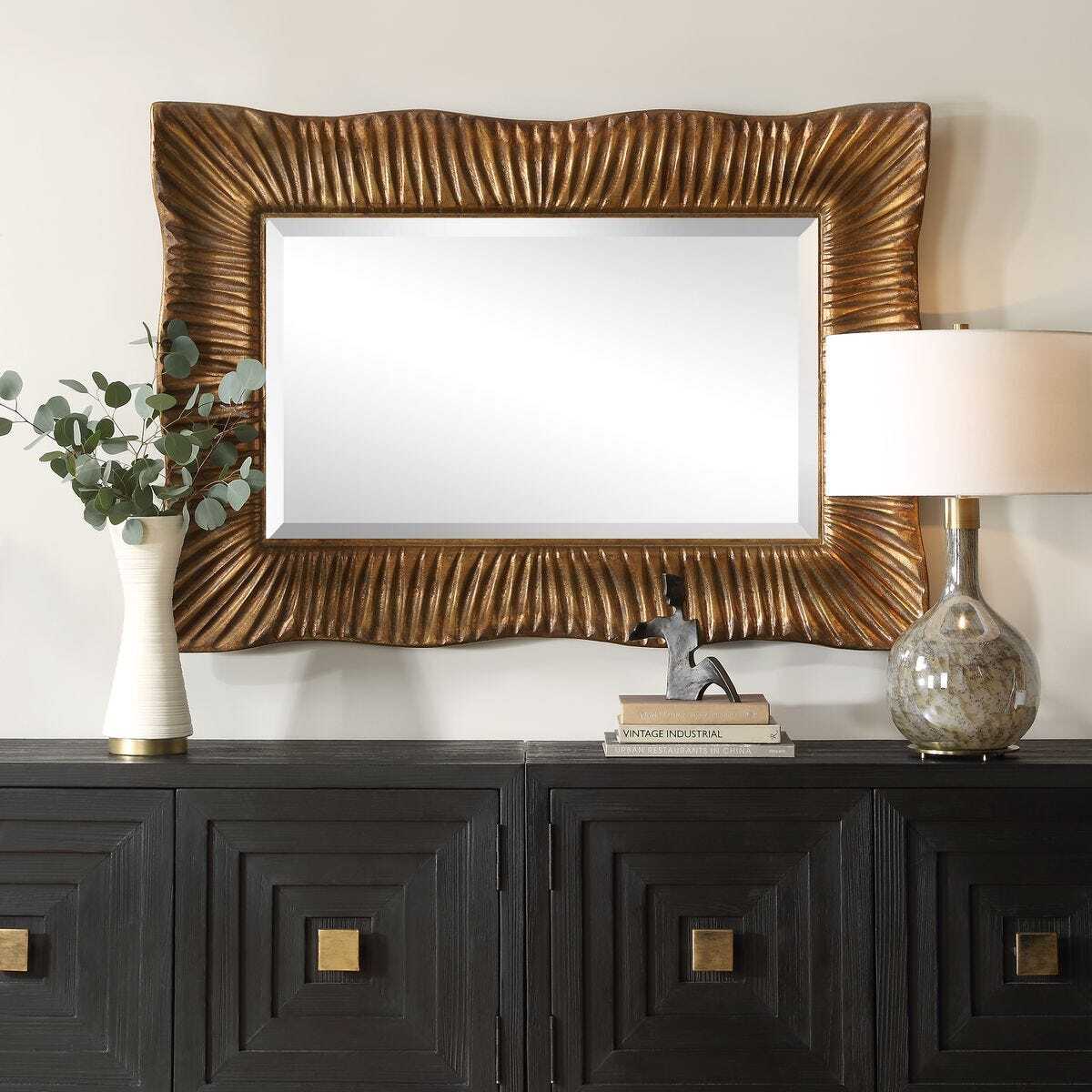 Decorative mirror with gold frame on a dark wooden console table.