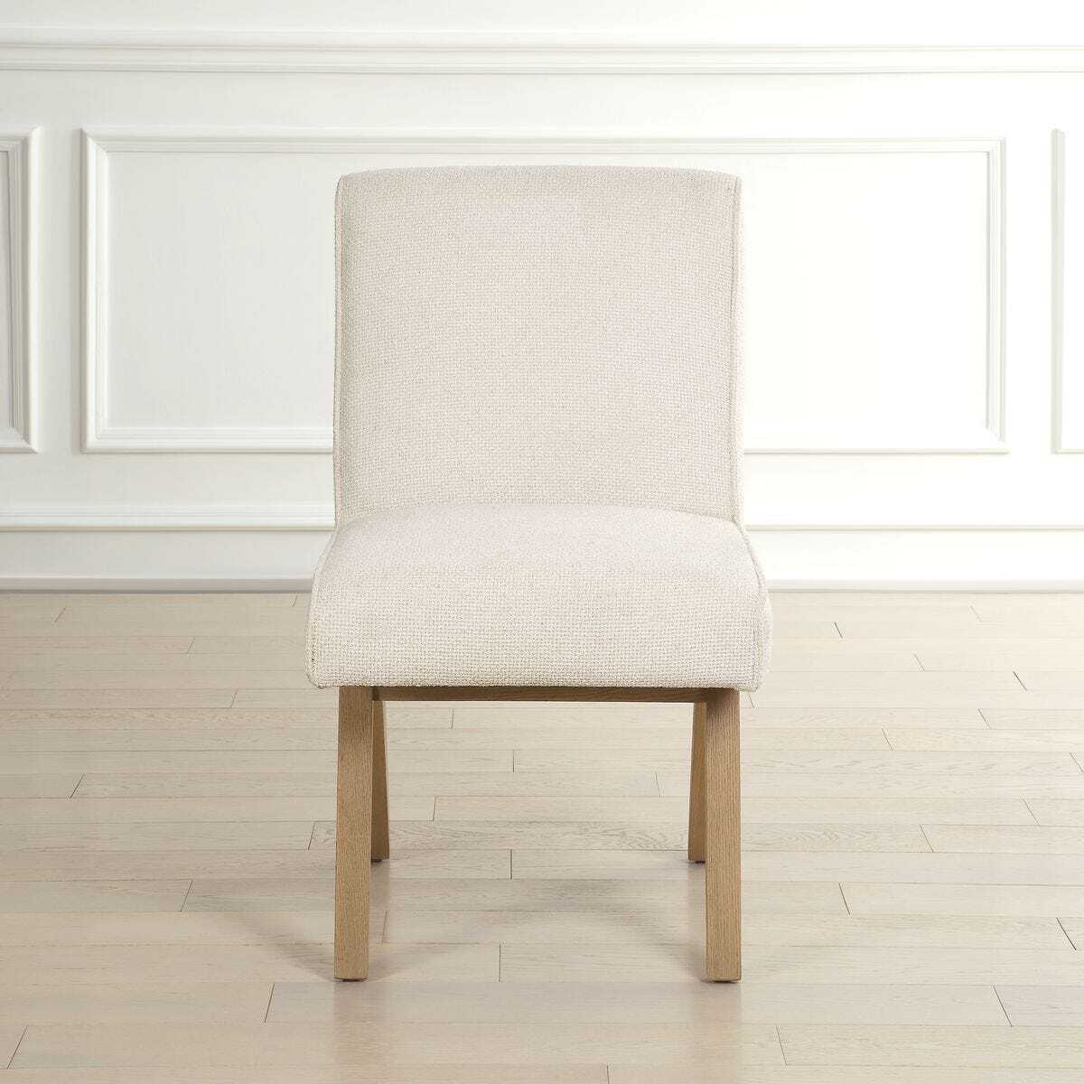 Beige upholstered chair with wooden legs on a light wood floor.